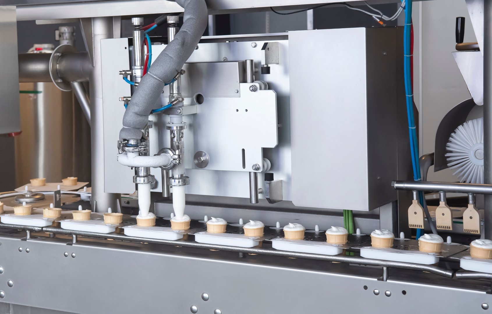 Automatic production line machine fills waffle cups with vanilla ice cream
