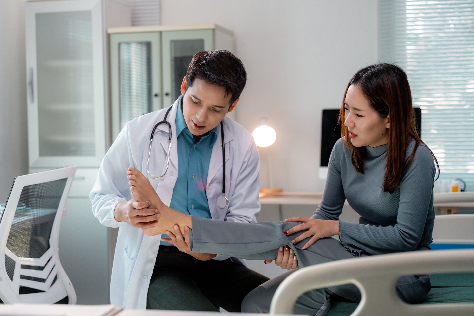Doctor examining the injured ankle of a young adult patient in a hospital room, focusing on healthcare and medical treatment while providing expert care and diagnosis