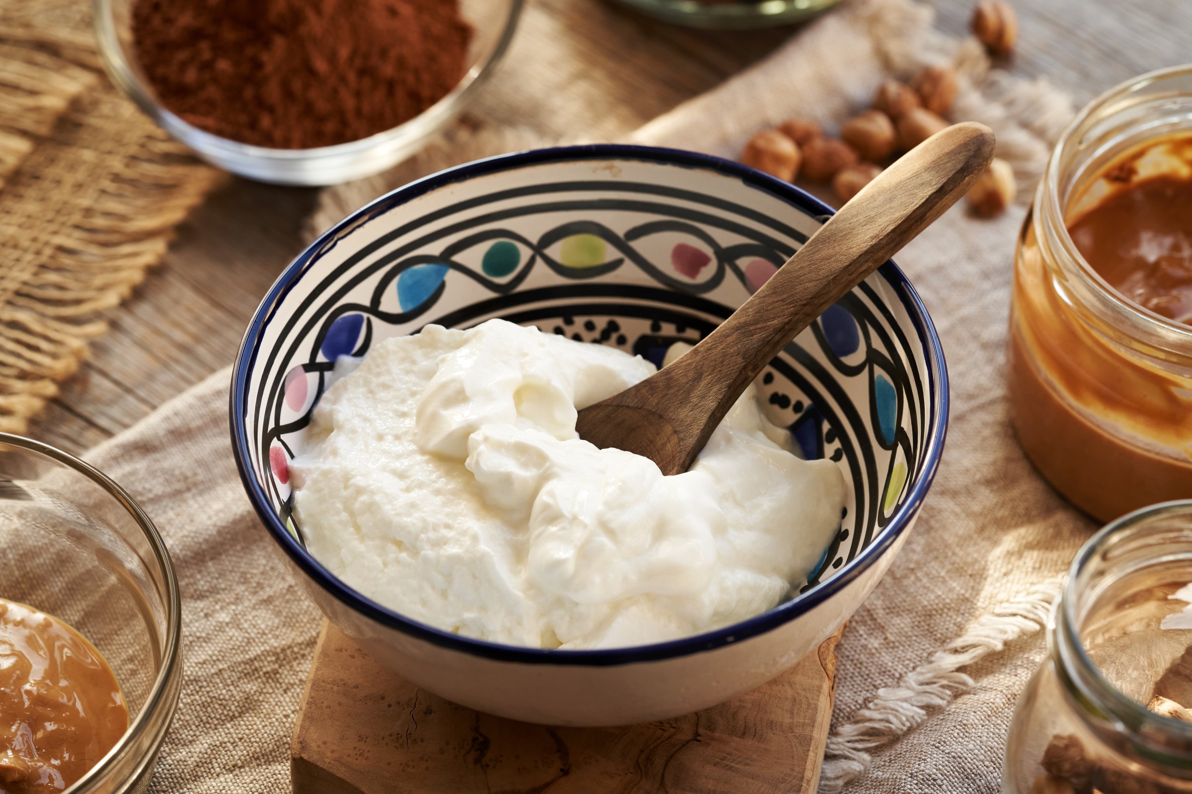 Greek yogurt in a bowl with nut butter, raw cacao and hazelnuts - ingredients for making healthy sweets