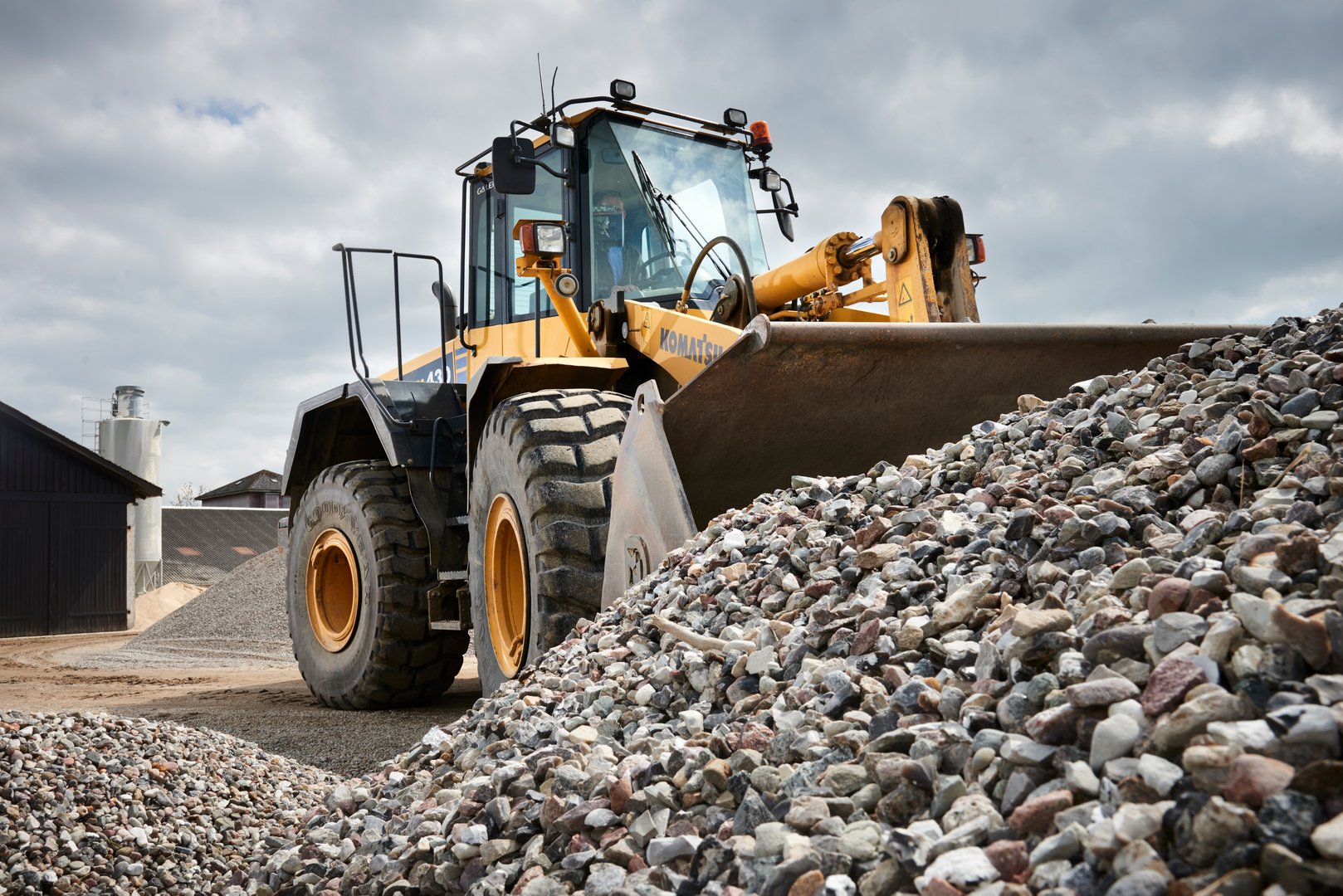 a red truck and a yellow excavator is moving sand and gravel on a nice sunny day.