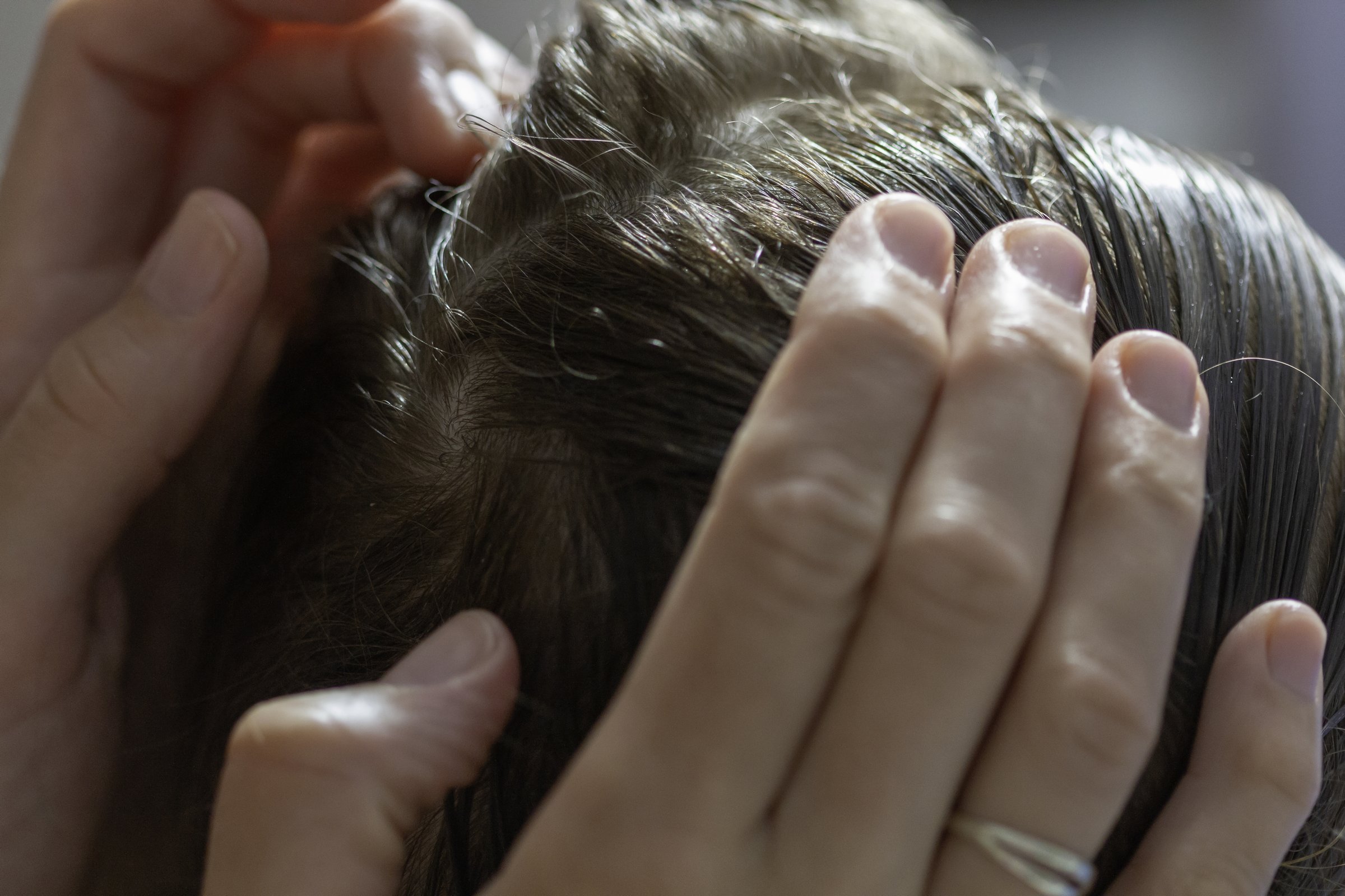 A closeup of a mother checking the hair of her daughter against lice