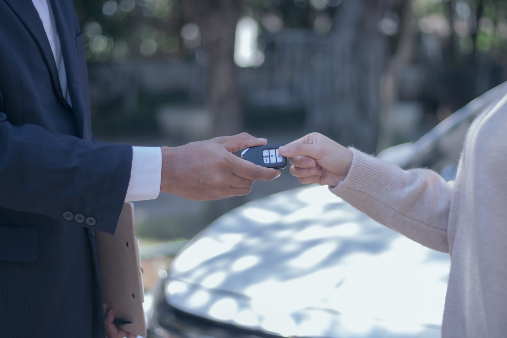 A young male car sales representative and a beautiful female customer are making a new car repair sign outdoors on a city road.