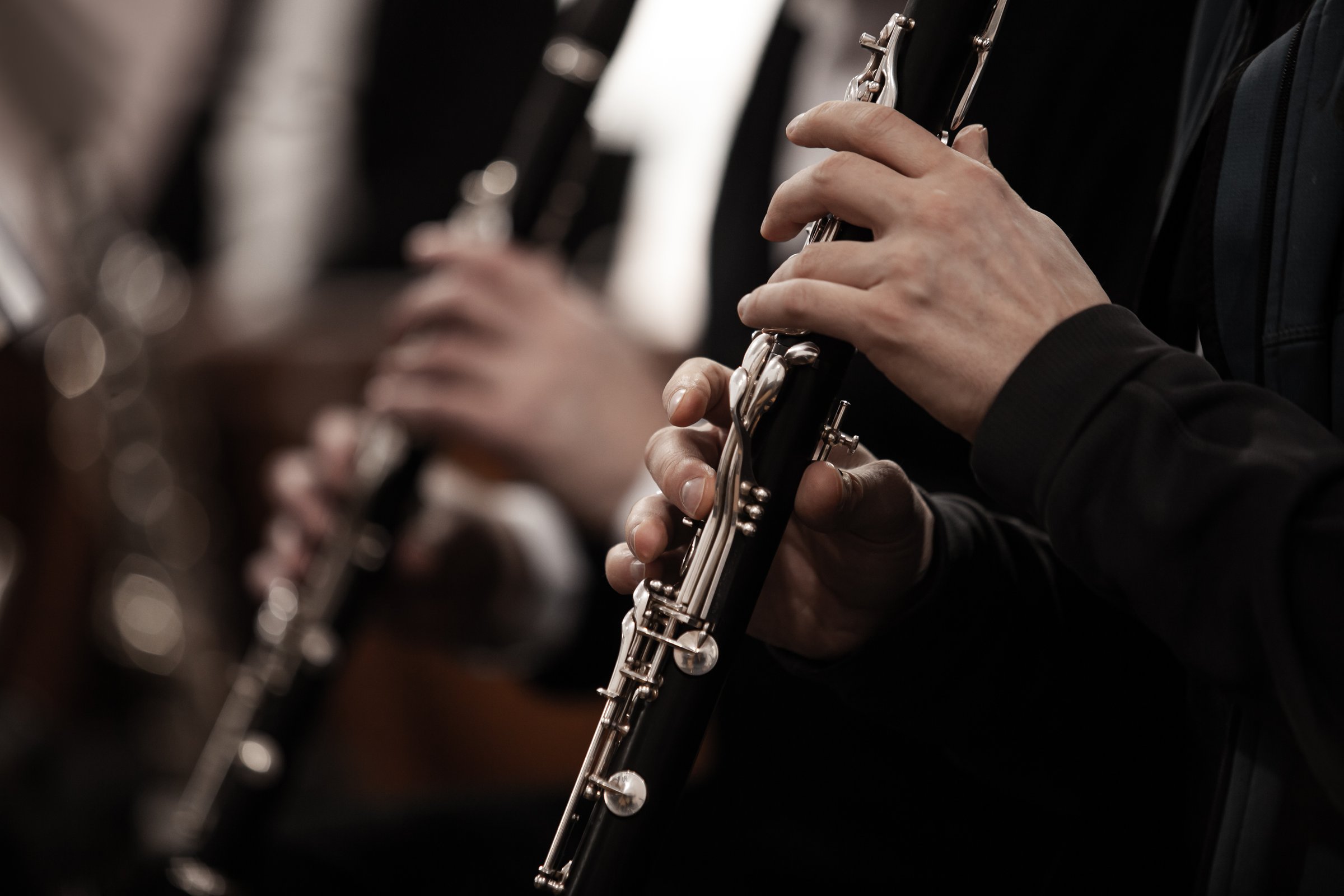 Close-up of musician's hands playing clarinet in orchestra