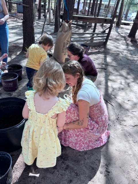 Teacher helping young children plant and work with soil during a nature-based Waldorf-inspired parent-child program at Wondering Woods Farm