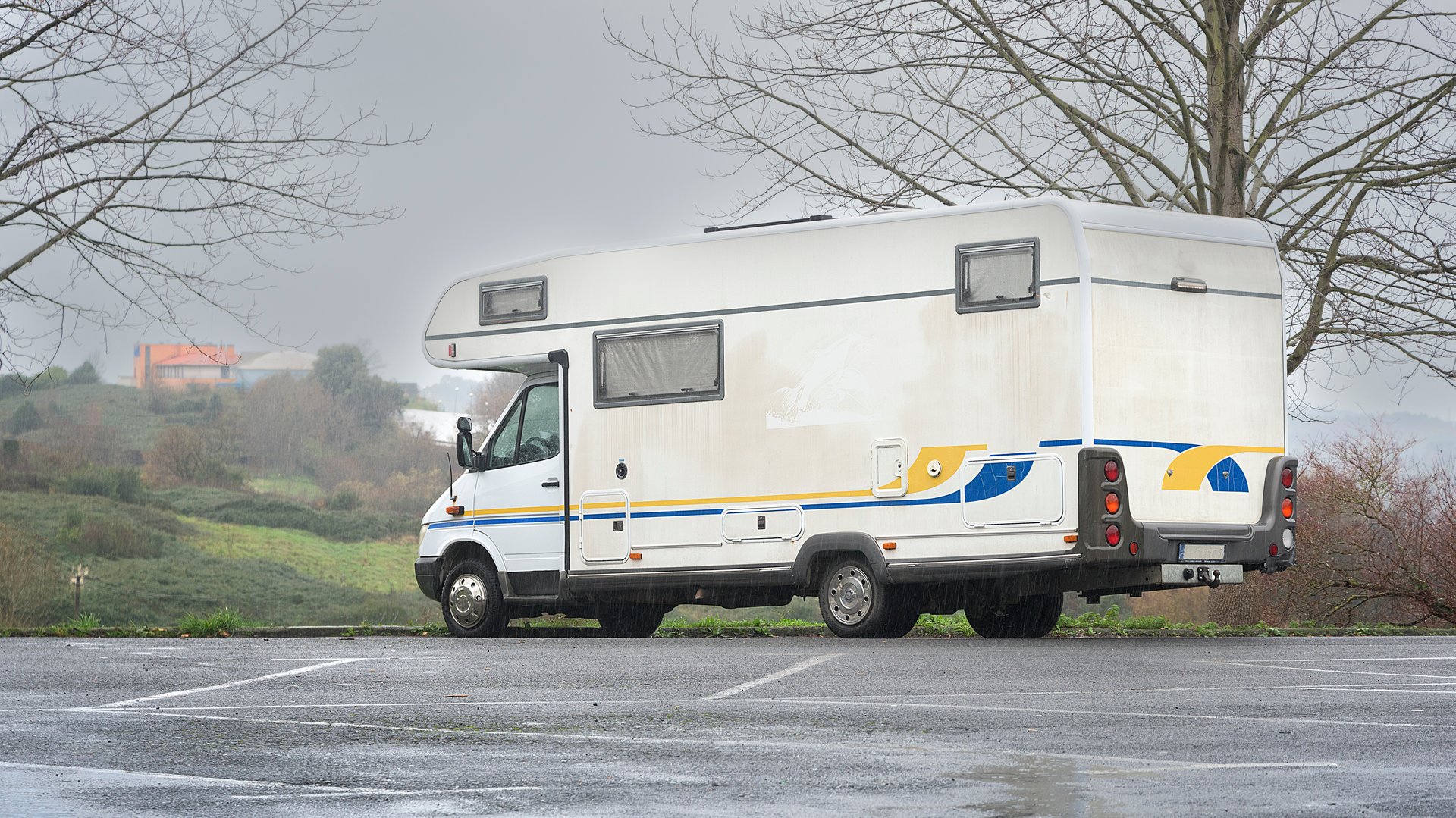 Motorhome parked in a parking lot in Akarlanda, Bizkaia, on a rainy morning. Winter tourism concept