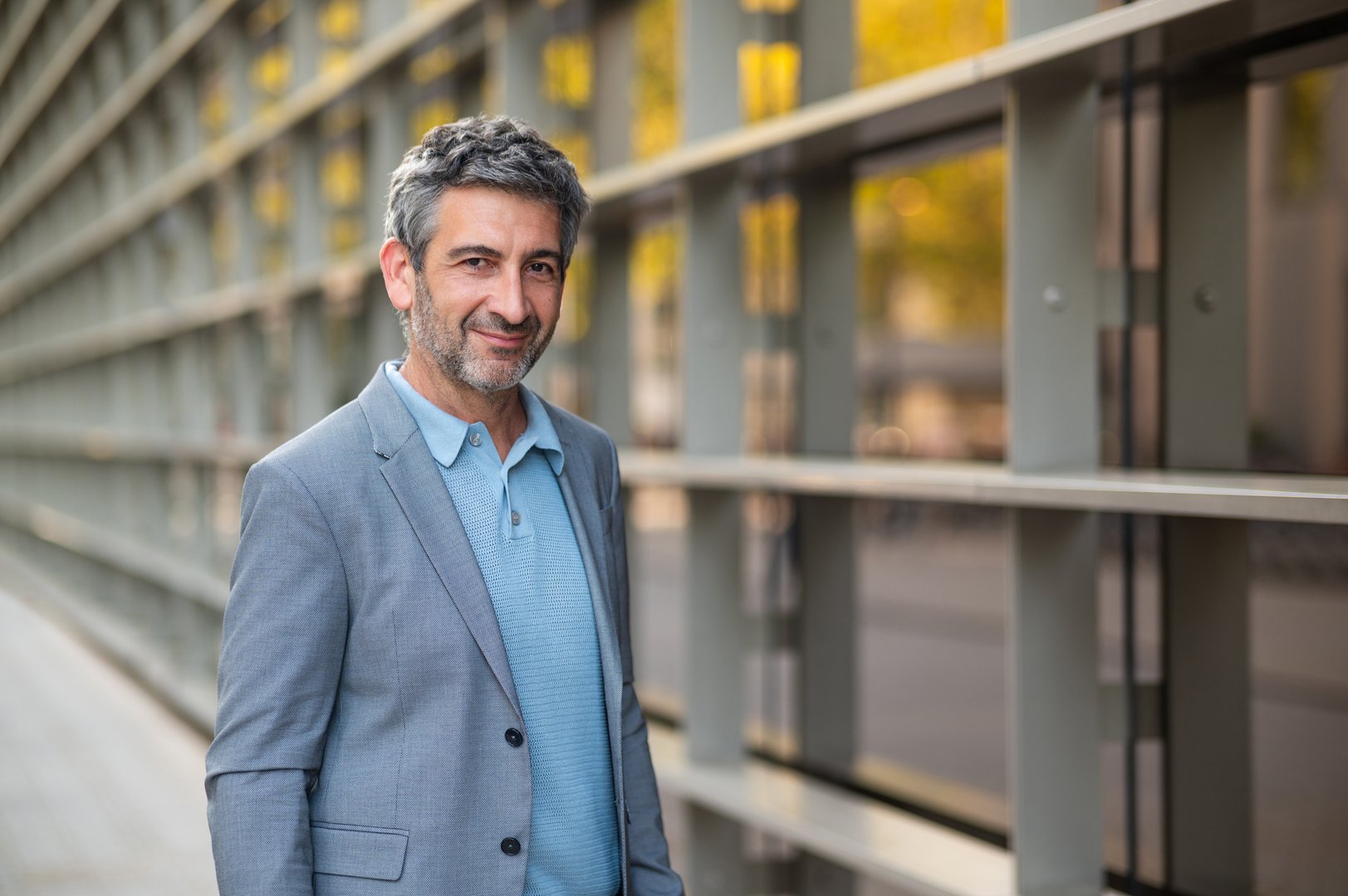 Confident man smiling at camera while standing against a modern office building outdoors