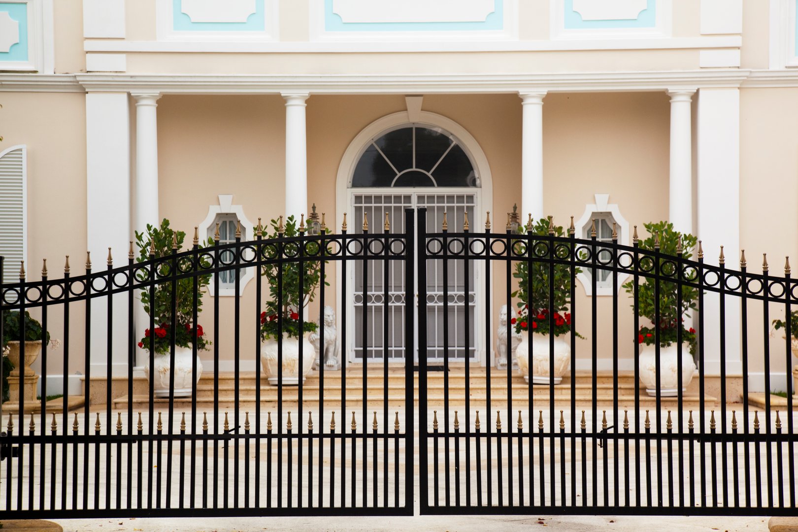 Facade of luxury home showing black wrought iron gate.