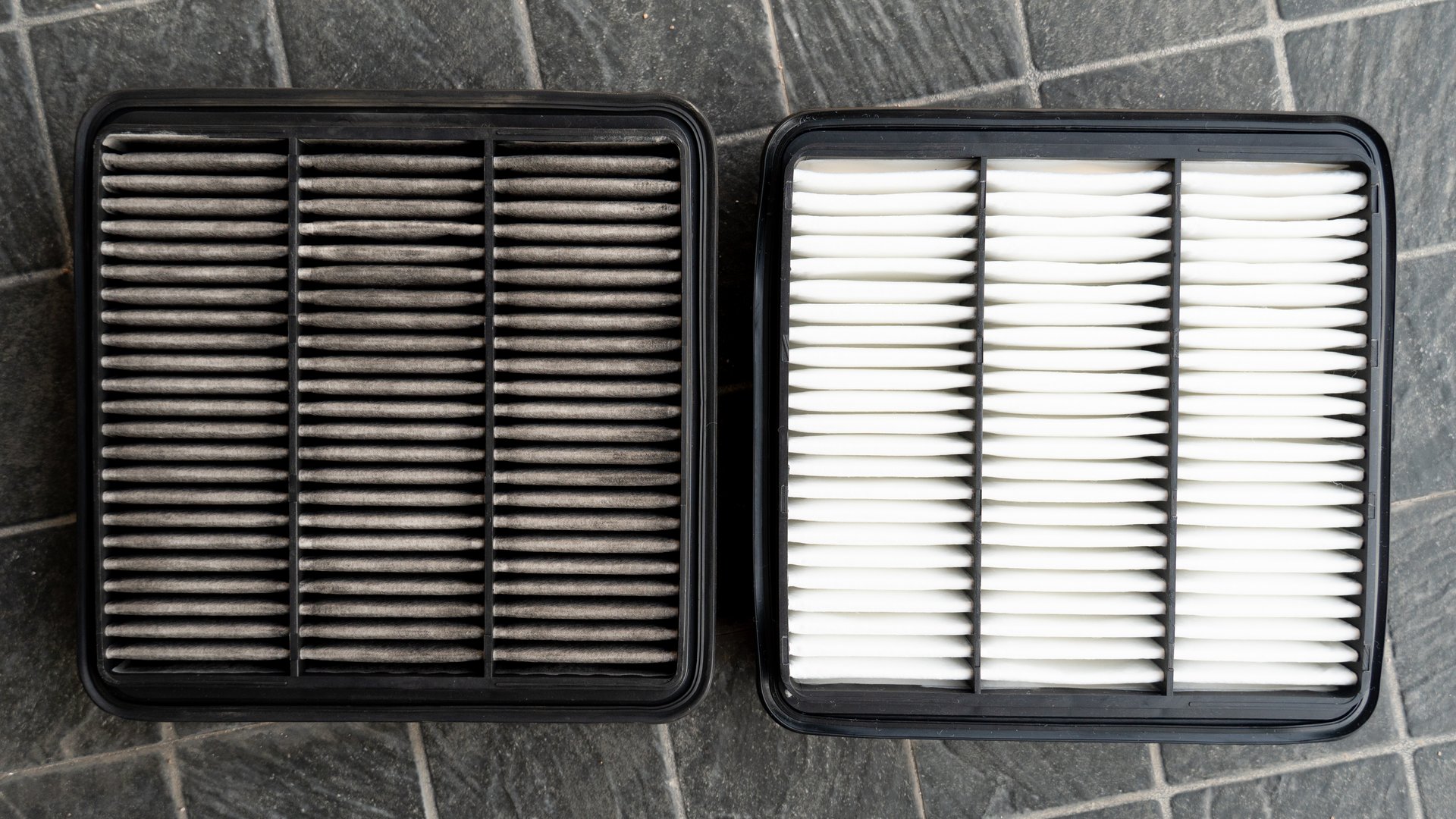 Front of old and new filters. Comparison between new and old is different. Placed on a black tiled floor.