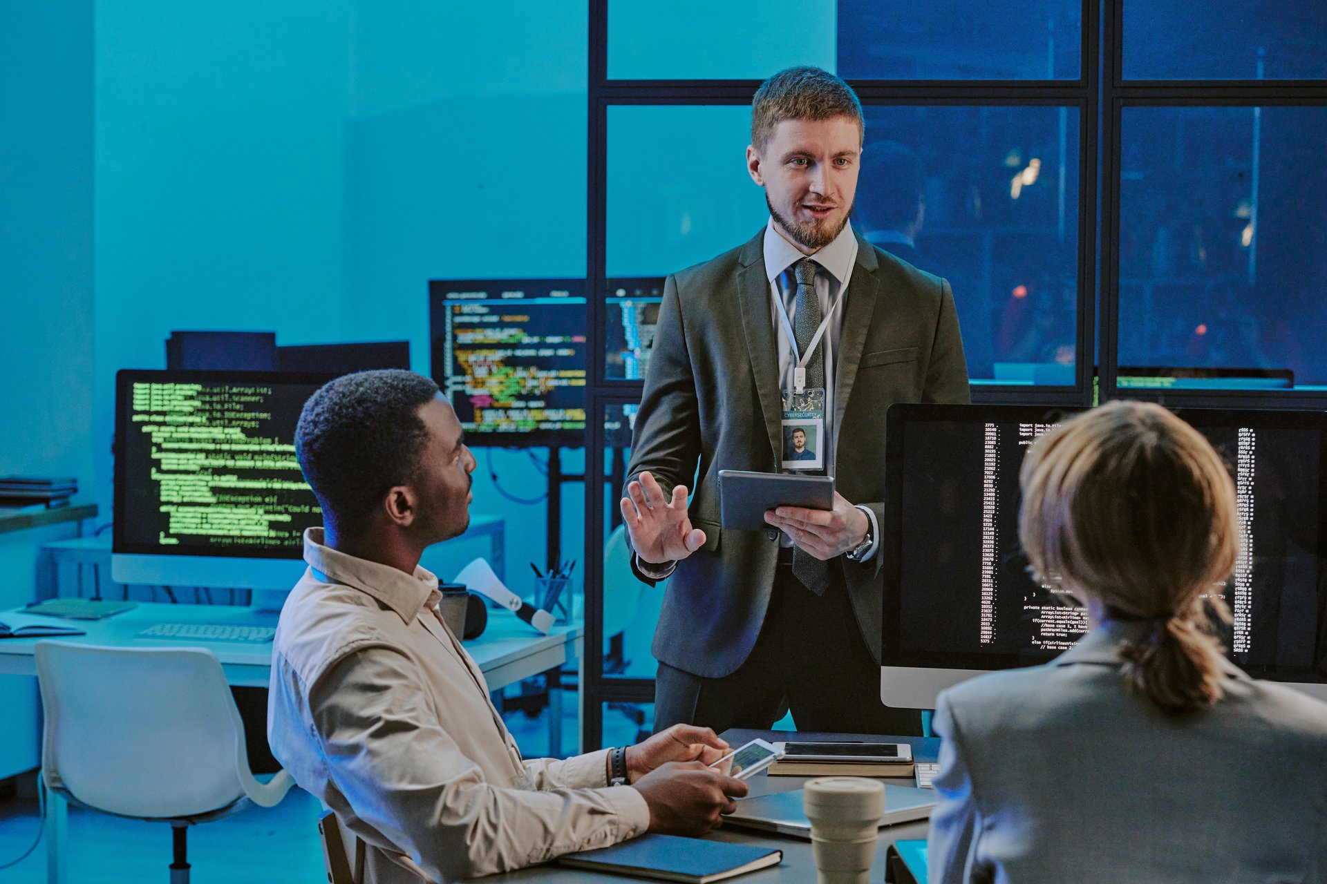 Ambitious young man standing in front of his colleagues suggesting plan on upgrading cybersecurity system during meeting in IT office