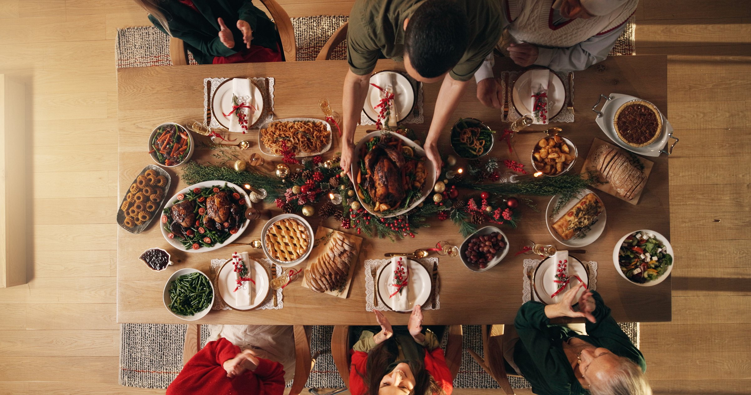 Festive, reunion and people in home, dinner and celebration of Christmas with food at night or meal. Above, group and family with feast for thanksgiving, evening and together on holiday in house