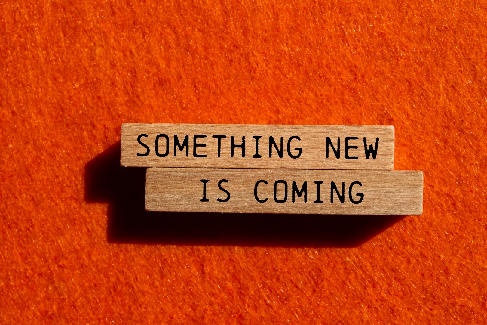 Something new is coming message written on wooden blocks on orange felt background. Conceptual something new is coming symbol. Copy space.