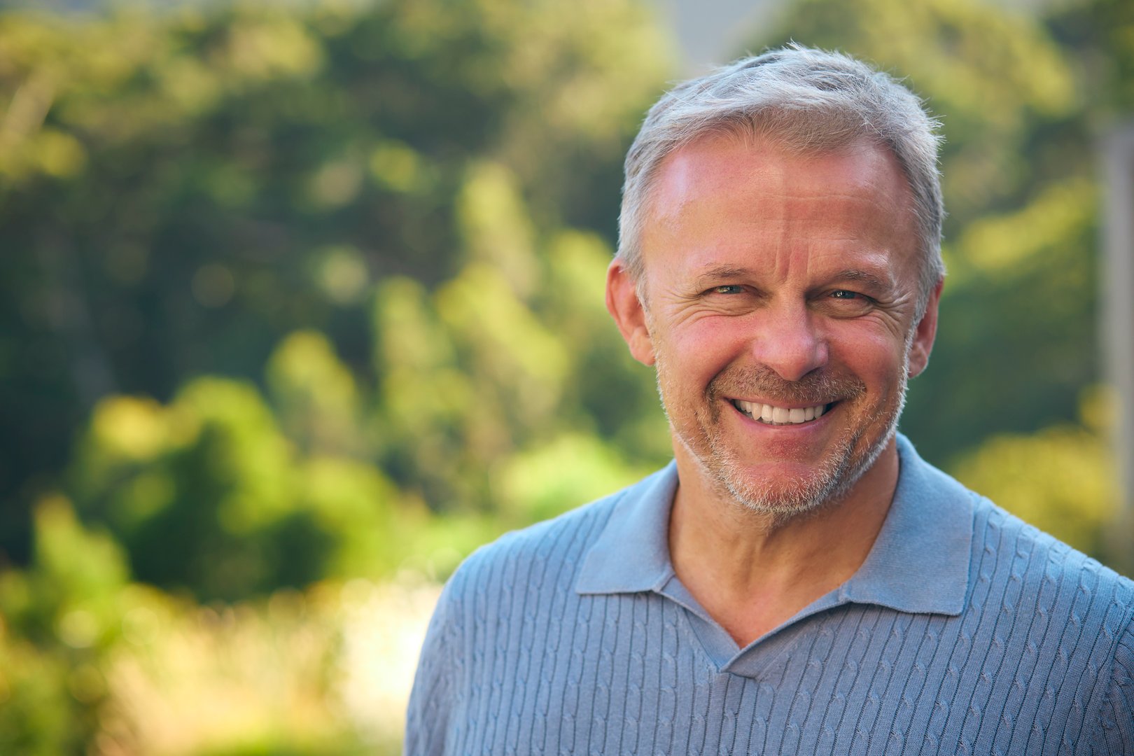 Portrait Of Laughing And Smiling Mature Man Standing Outdoors In Countryside