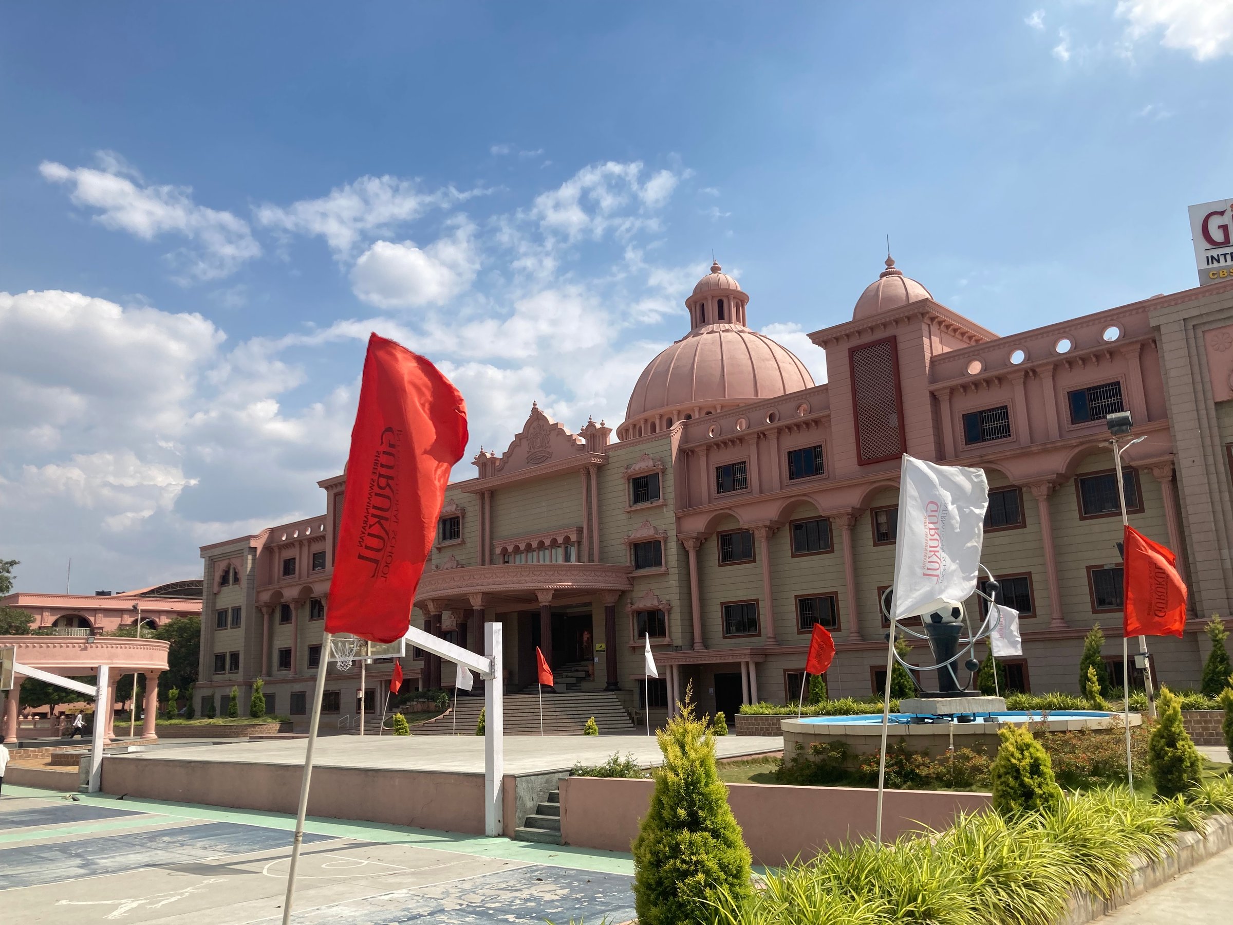 Large pink building with dome, surrounded by red and white flags, under a blue sky.