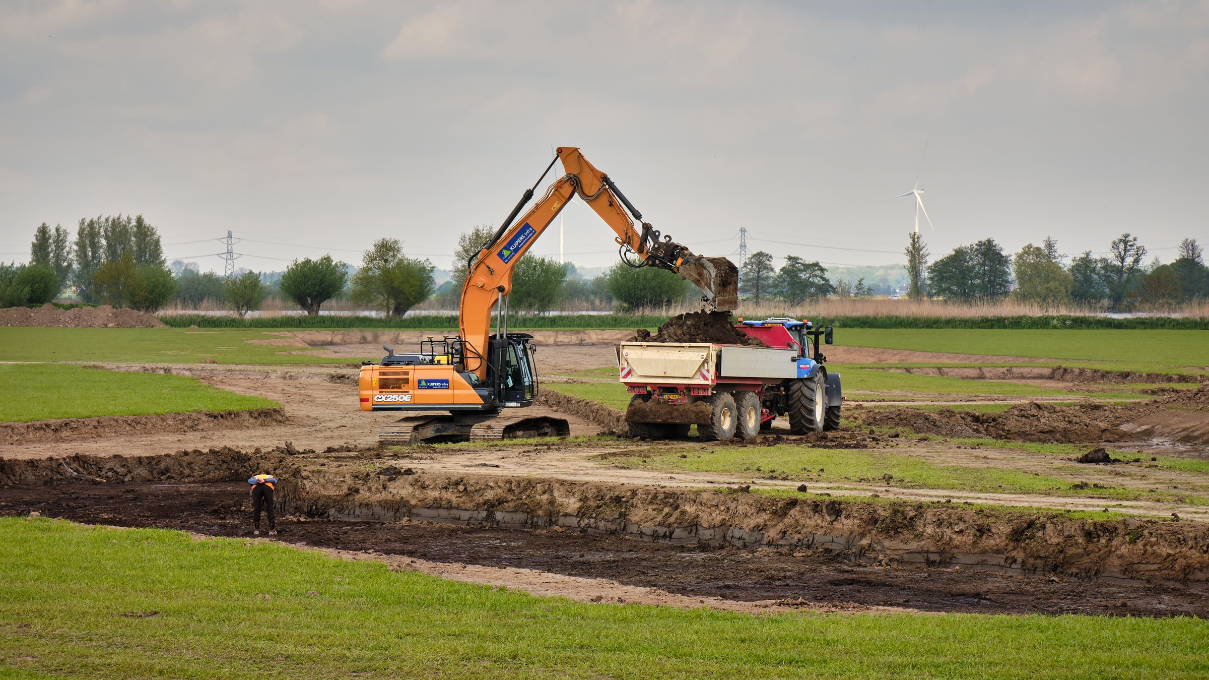 April 22, 2025 - Westmaas-Netherlands: Excavator loading soil into a trailer during nature restoration works in polder Het Munnikenland, replacing former farmland.