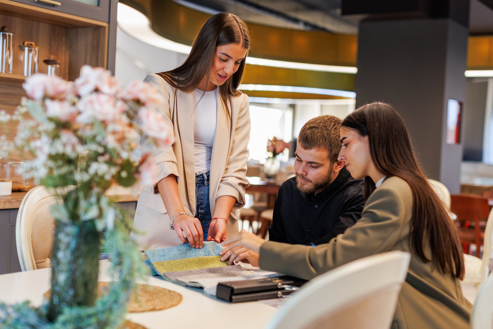 Interior designer presenting fabric samples and discussing choices with a couple in a furniture showroom