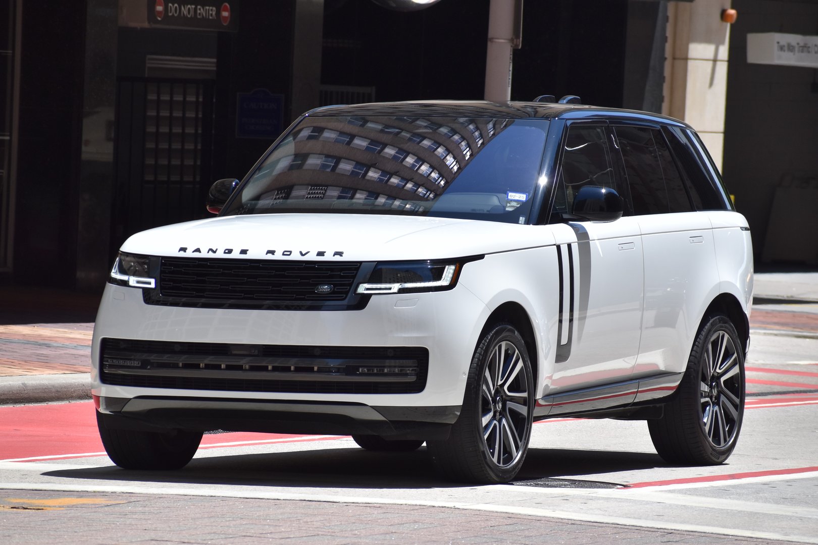 Houston, TX USA - 5/15/2024 - A portrait of a black and white Land Rover Range Rover SUV cruising in a downtown district