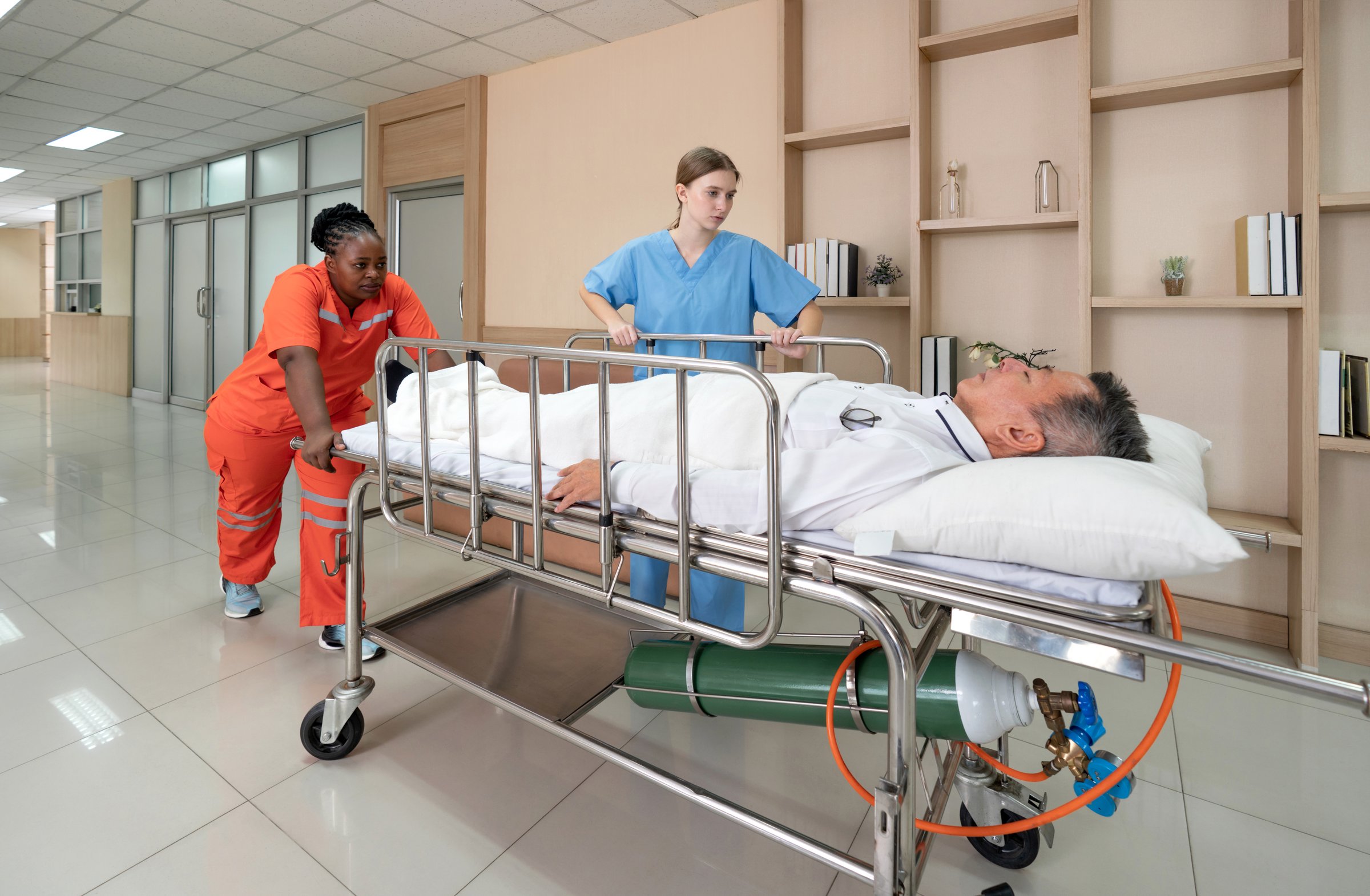 Two healthcare worker are hurriedly transferring a patient on a stretcher in a  well-lit hospital hallway during the day, illustrating urgency and teamwork in medical care.