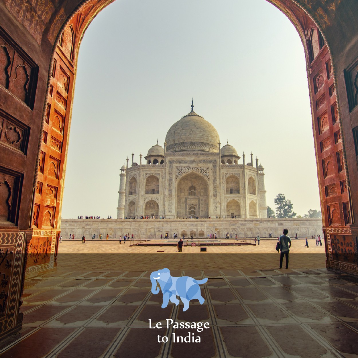 View of the Taj Mahal through an arched doorway, with tourists walking on the marble platform. Le Passage to India logo visible.