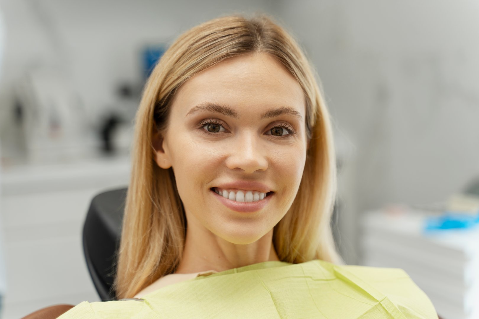 Portrait of happy patient showing perfect teeth after dental treatment, enjoying healthy smile in dentist office