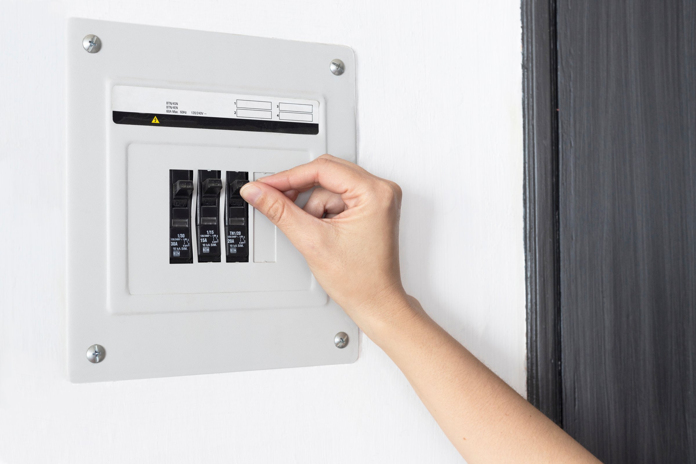 Person resetting the circuit breaker at the electrical panel