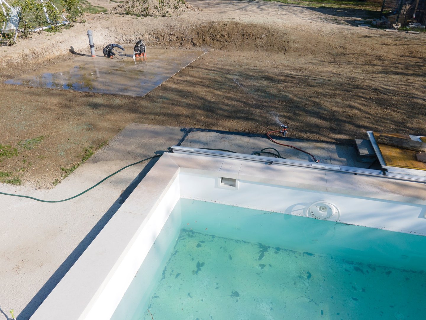 Drone flight over fresh earth area with grass grown next to pool construction site in April