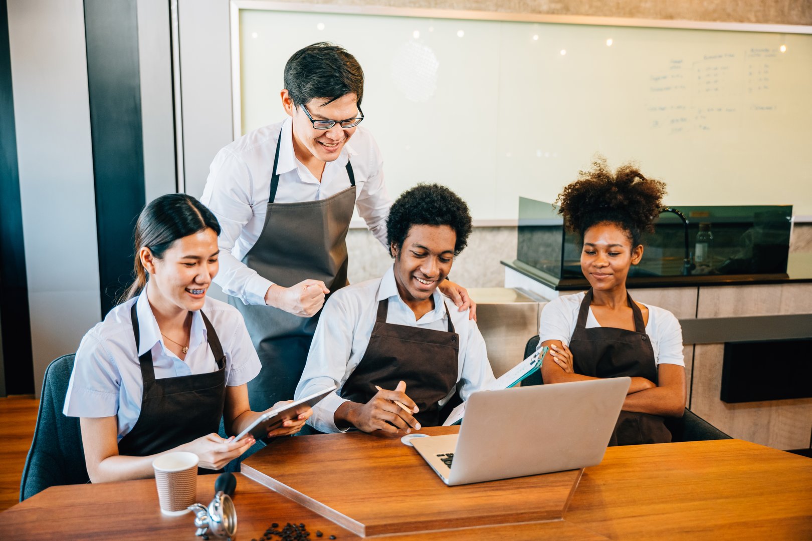 Diverse Unternehmer führen Teambesprechung in stilvollem Café - Symbolbild für professionelle Serviceleitung und Teamkoordination in der Gastronomie