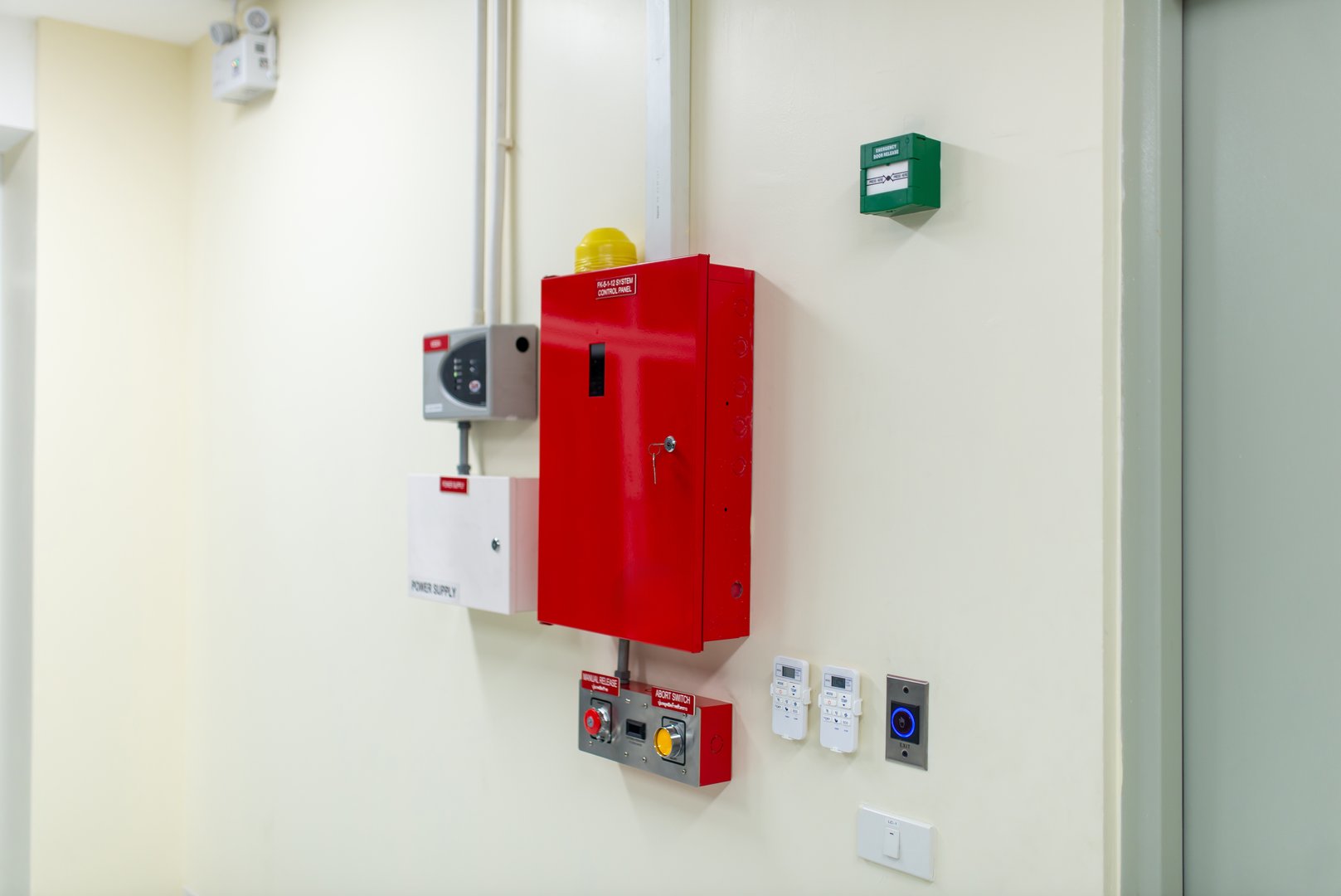 This image features fire safety equipment installed on the wall of a modern building, showcasing a red control panel and related devices for emergency response.