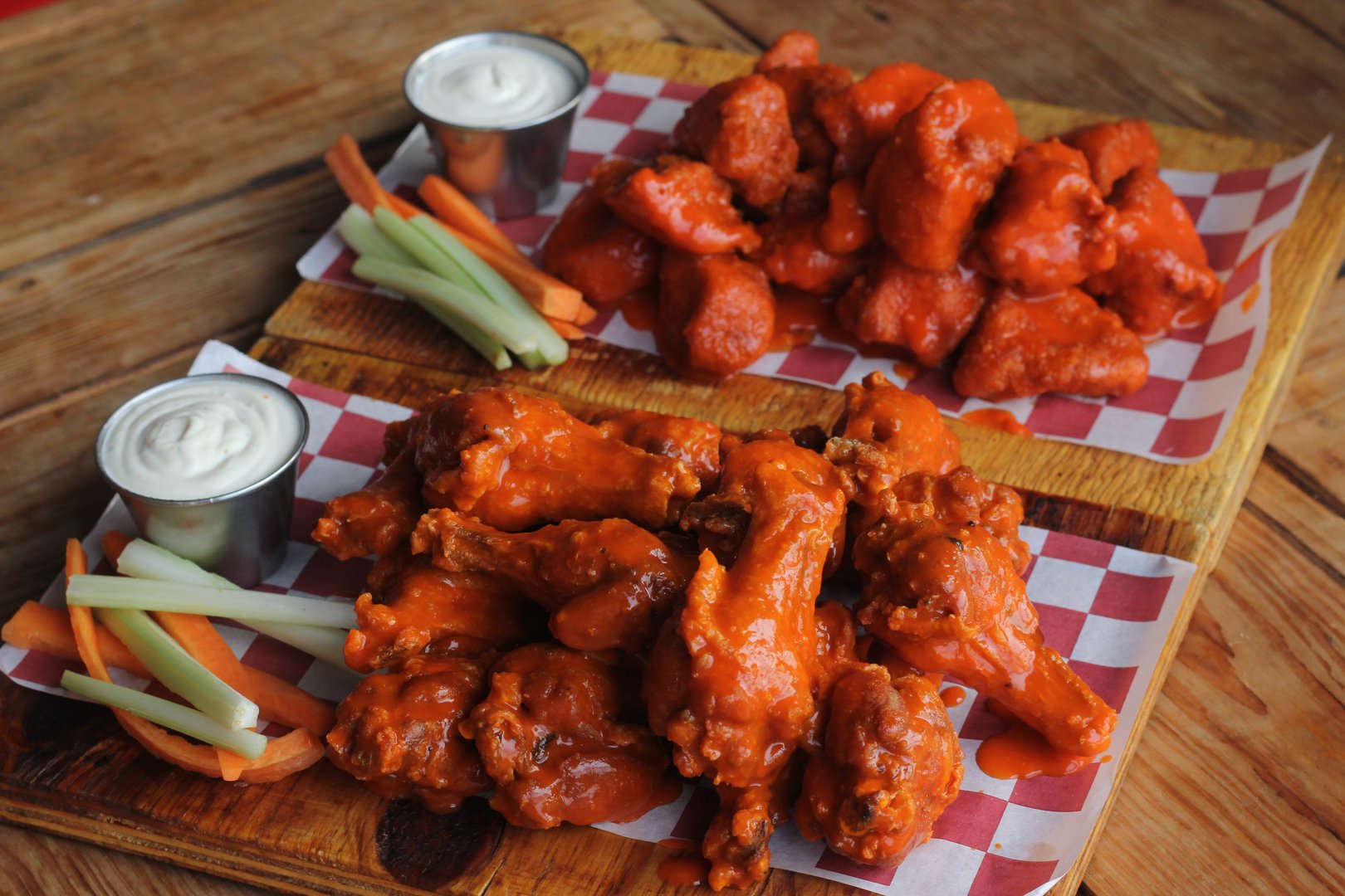 This enticing image features a platter of buffalo chicken wings and boneless accompanied by celery sticks and dipping sauces, ideal for gatherings and casual dining experiences.