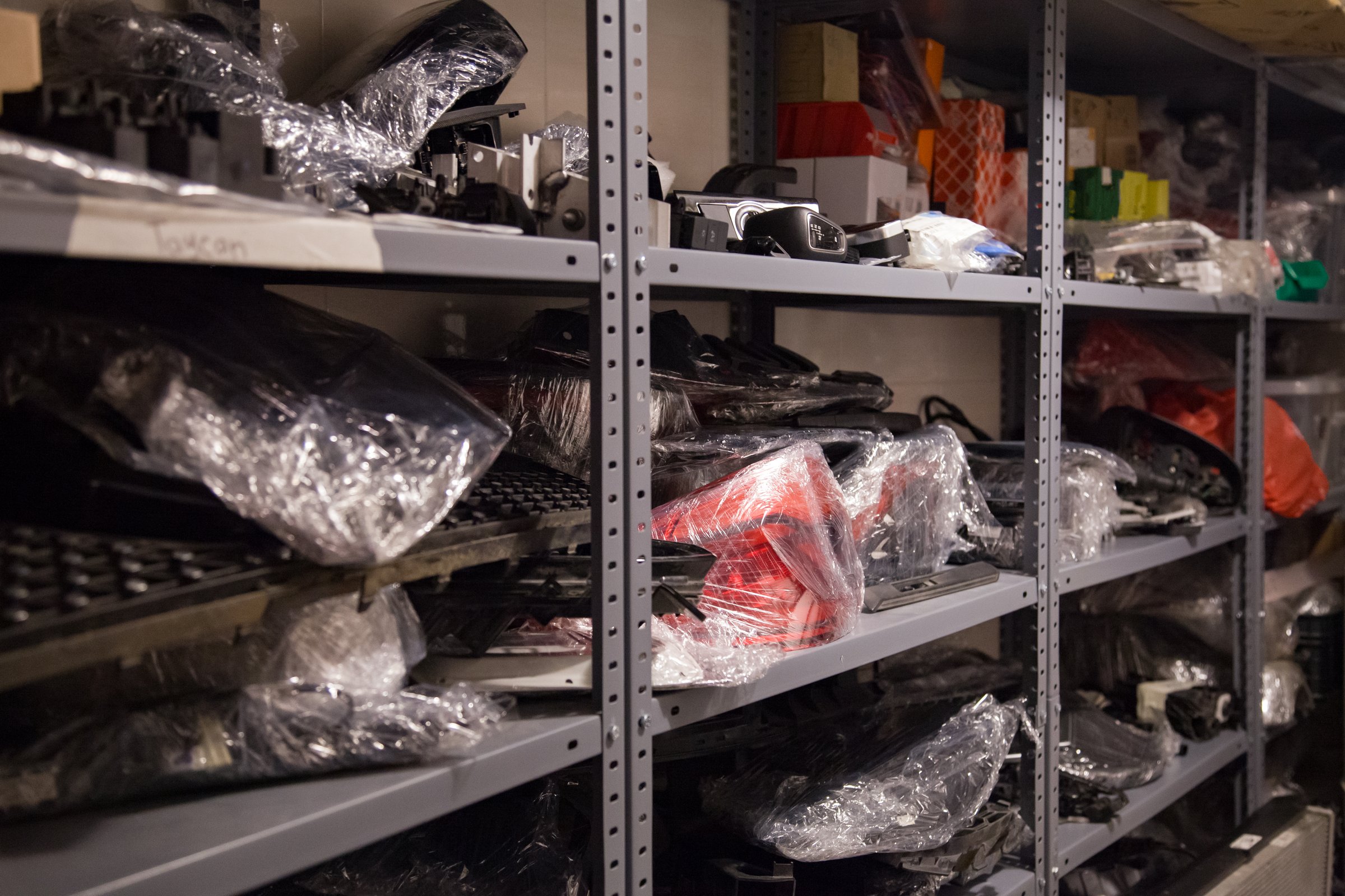 Metal shelves with various car parts from new modern vehicles in an auto repair shop