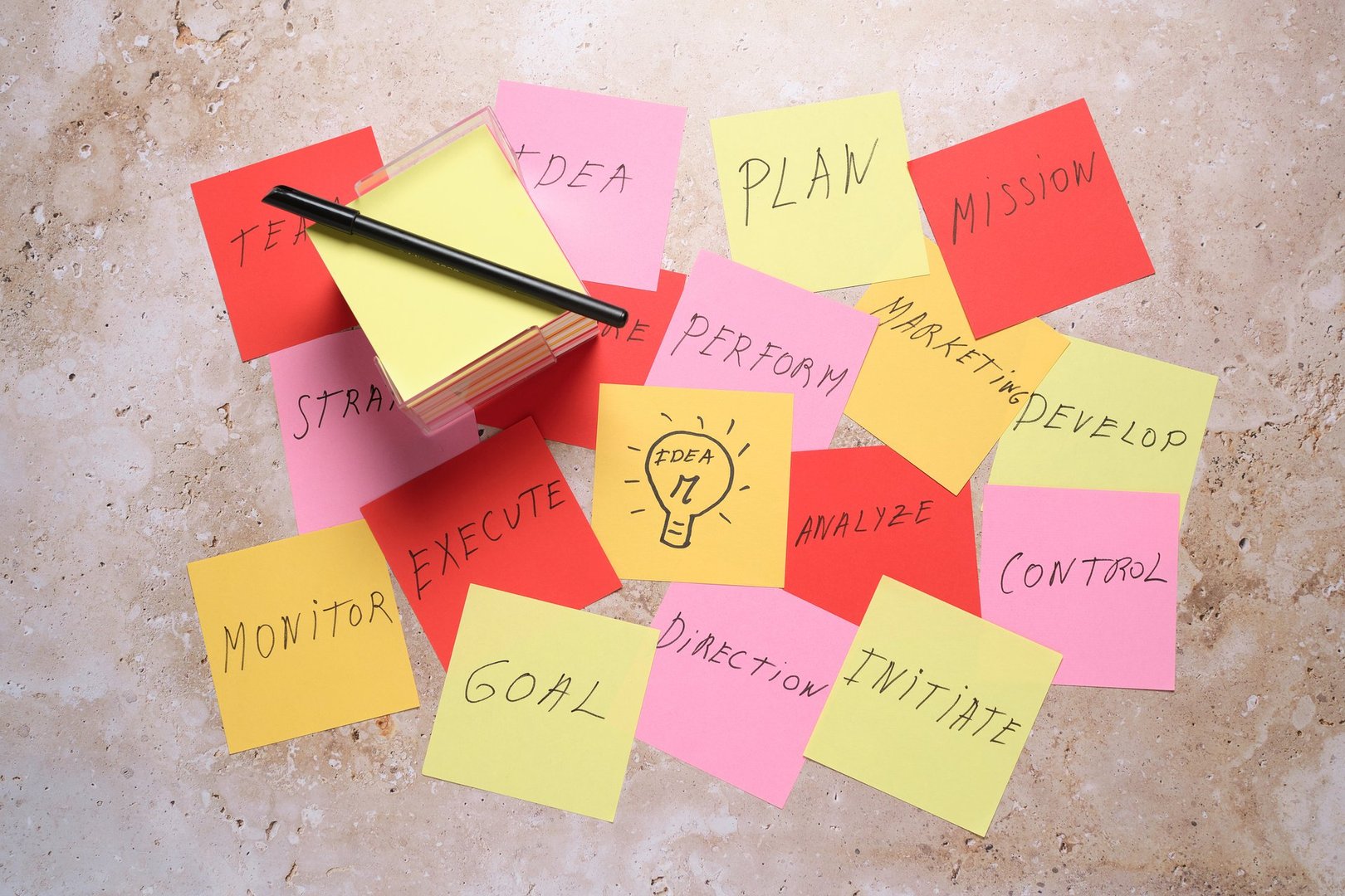 Colorful sticky notes scattered around a transparent holder with a pen on a desk, showcasing concepts for planning, strategies, and project execution at work.