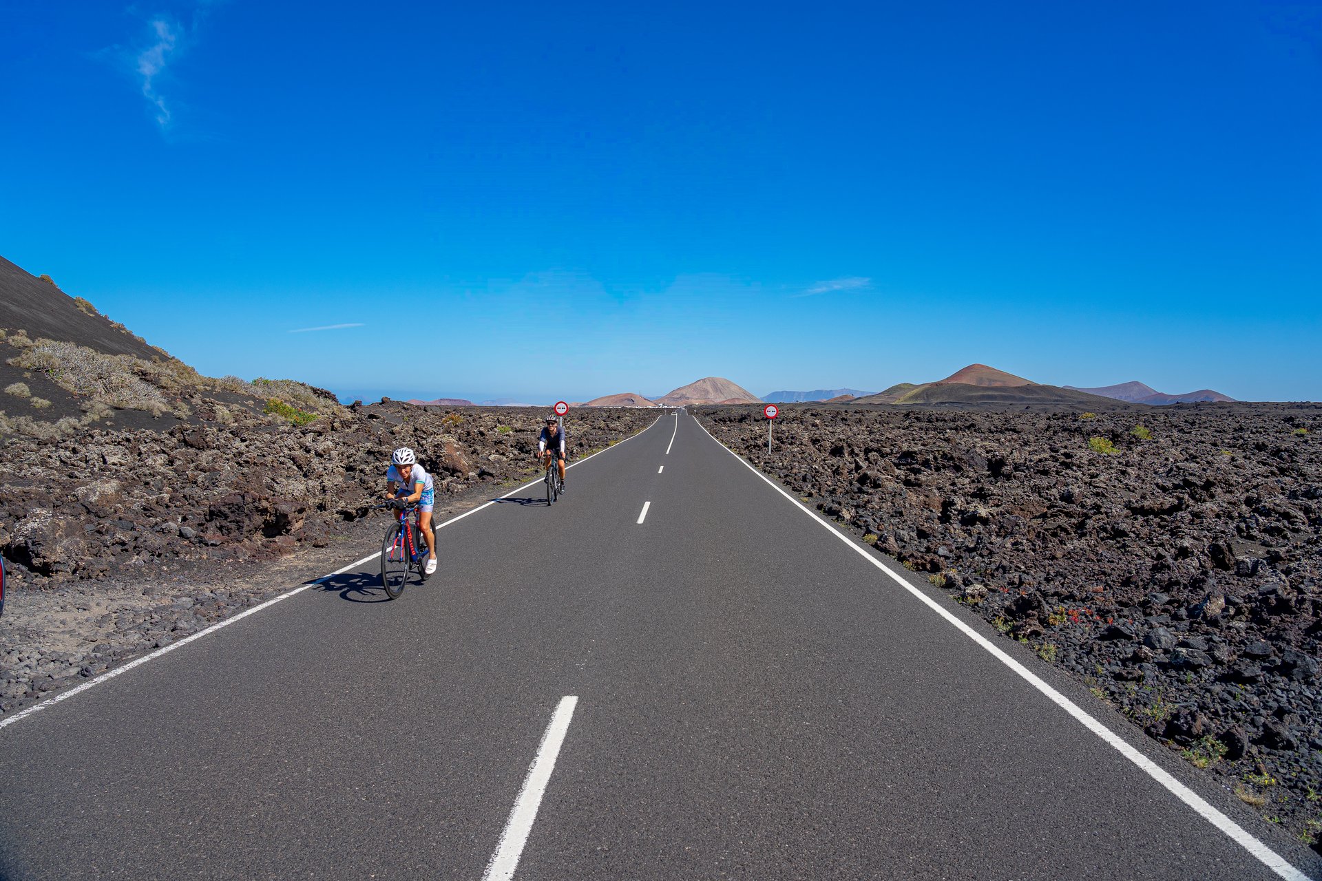 Small group of cyclists on a road surrounded by lava landscape. small group of cyclists on a road surrounded by lava landscape in Timanfaya National Park, Lanzarote, Canary Islands, Spain.