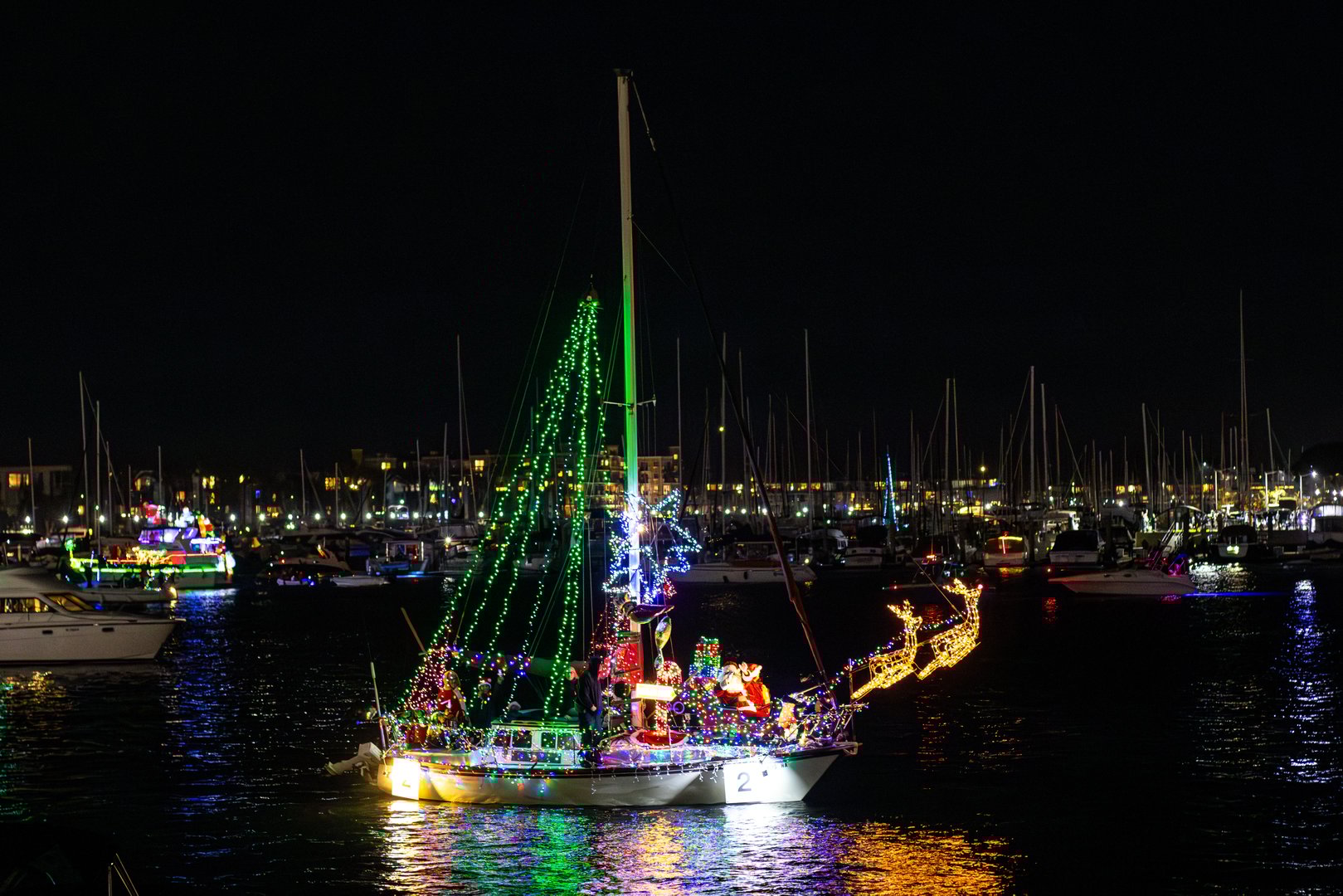 Sailboats and yachts in the Marina del Rey Holiday Boat Parade in Los Angeles, California. Boat owners and sailing clubs decorated their watercraft with Christmas lights for the annual holiday tradition.