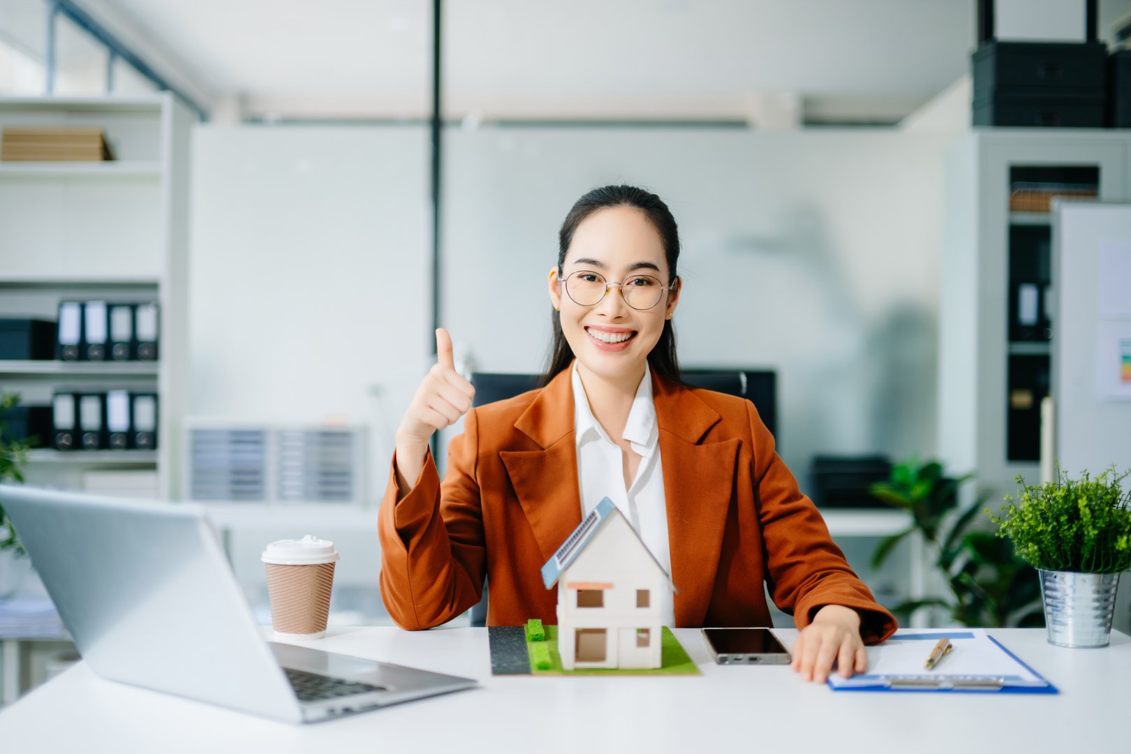 Confident real estate agent presenting house models in office