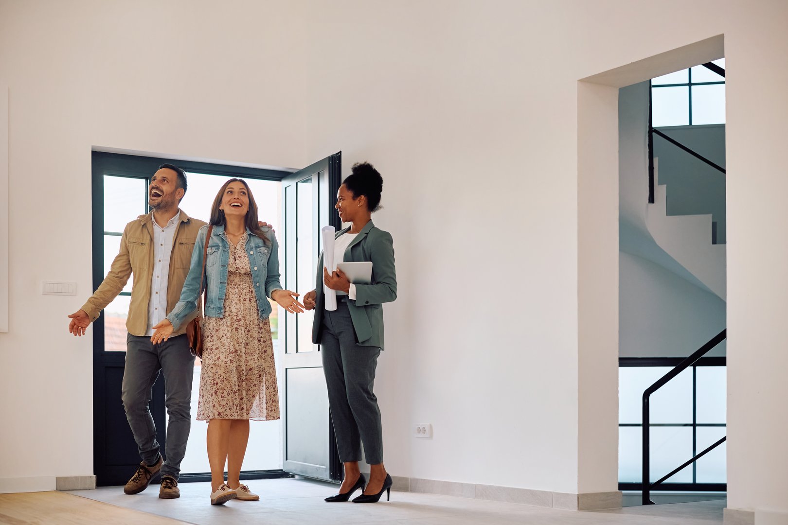 Excited couple entering in a new house while meeting with their real estate agent. Copy space.
