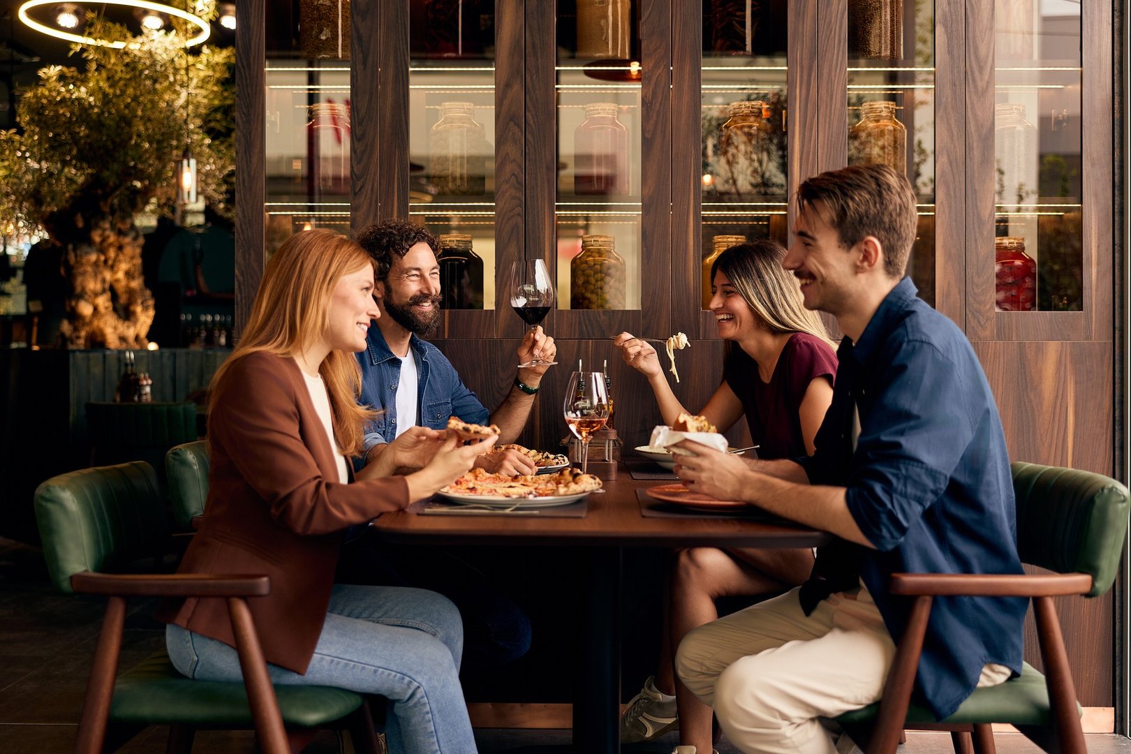 Group of friends sharing a meal and enjoying conversation at a restaurant table.