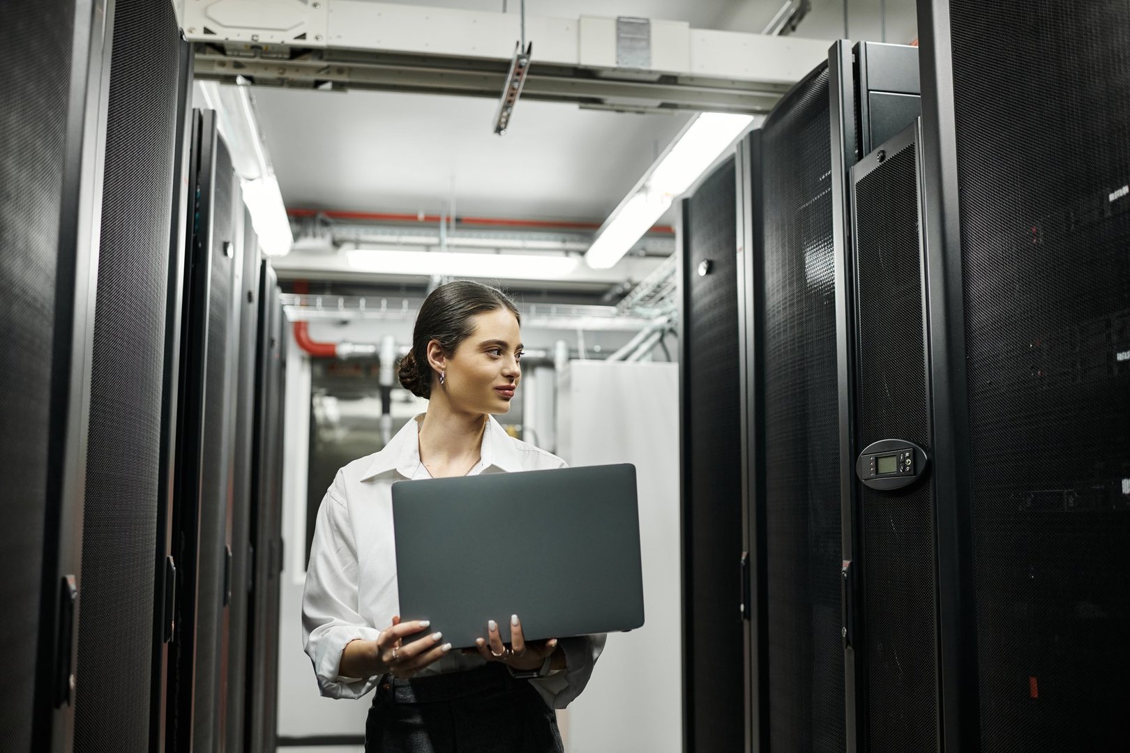 A young woman is engaged in technical duties within a sleek data center, ensuring security.