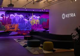 A vibrant mural with cityscape and skyline art, illuminated by purple lighting, in a modern interior with a Ketra logo on the wall.