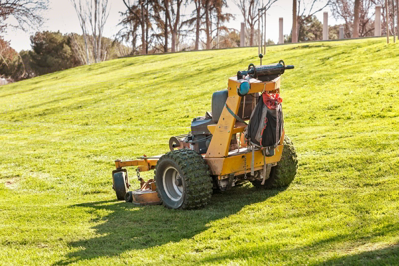 tractor mowing dirty grass after maintenance of a park meadow