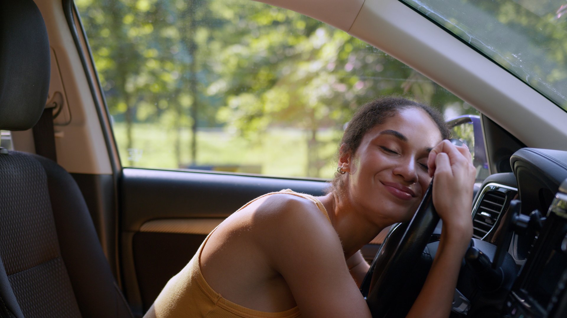 Happy African American woman buyer female sit luxury new car auto hugging wheel steering owner automobile buying enjoy businesswoman vehicle embrace hug rent service test drive cuddling girl business. High quality 4k footage