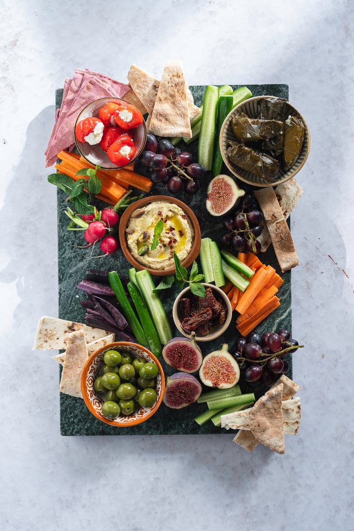 A colorful and tasty mezze platter with fresh spreads, dips, vegetables and olives