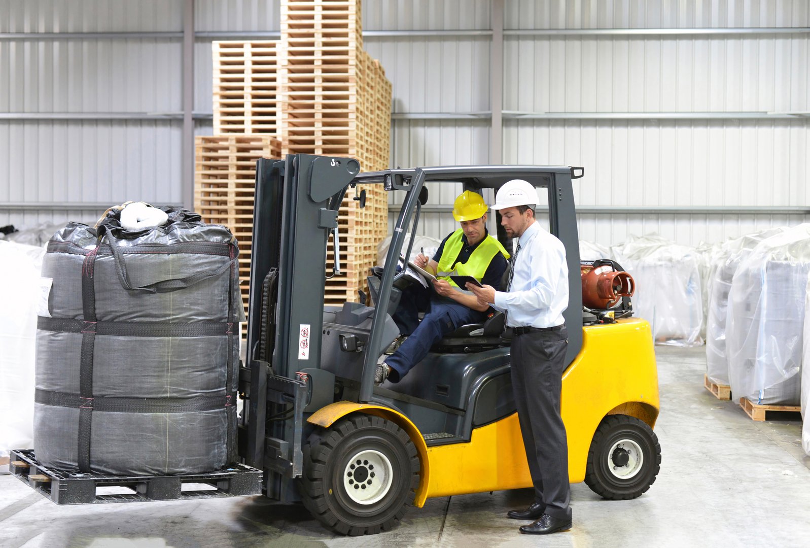 meeting of the manager and worker in the warehouse - forklift and interior of the industrial building