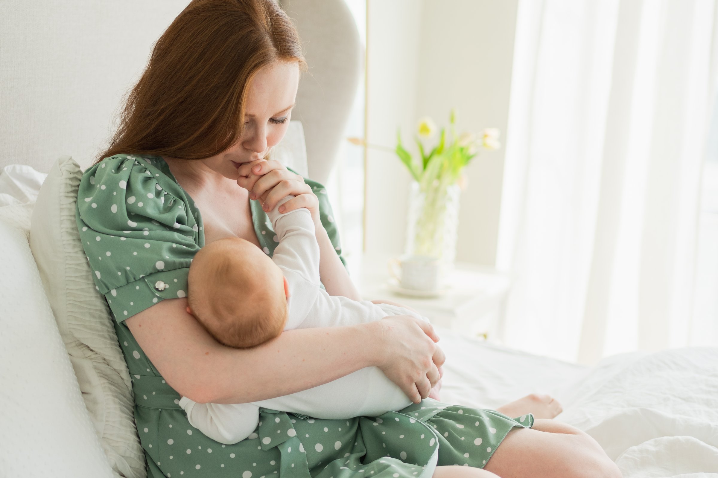 Happy family at home. Mother holding little toddler child daughter. Mom baby girl relax playing having fun together at home. Mother hugs baby with love care. Mom of breast feeding baby in living room