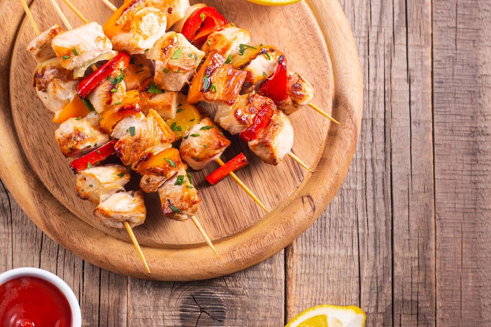 Delicious grilled chicken skewers with capsicum, lemon, salad and ketchup on a plate over the table. Chicken kebab. Healthy food concept.