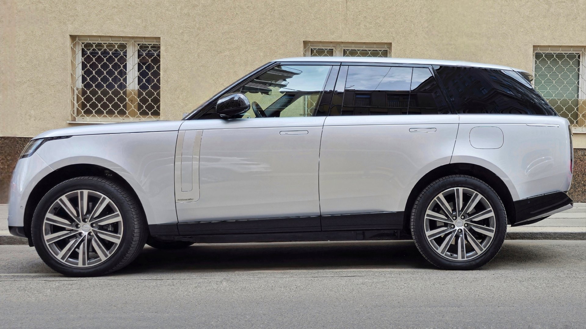 Side view of a Range Rover L460 luxury SUV parked on a city street, featuring flush door handles and 22-inch alloy wheels, dhowcasing its distinctive design and styling. Vienna, Austria, April, 4, 2025