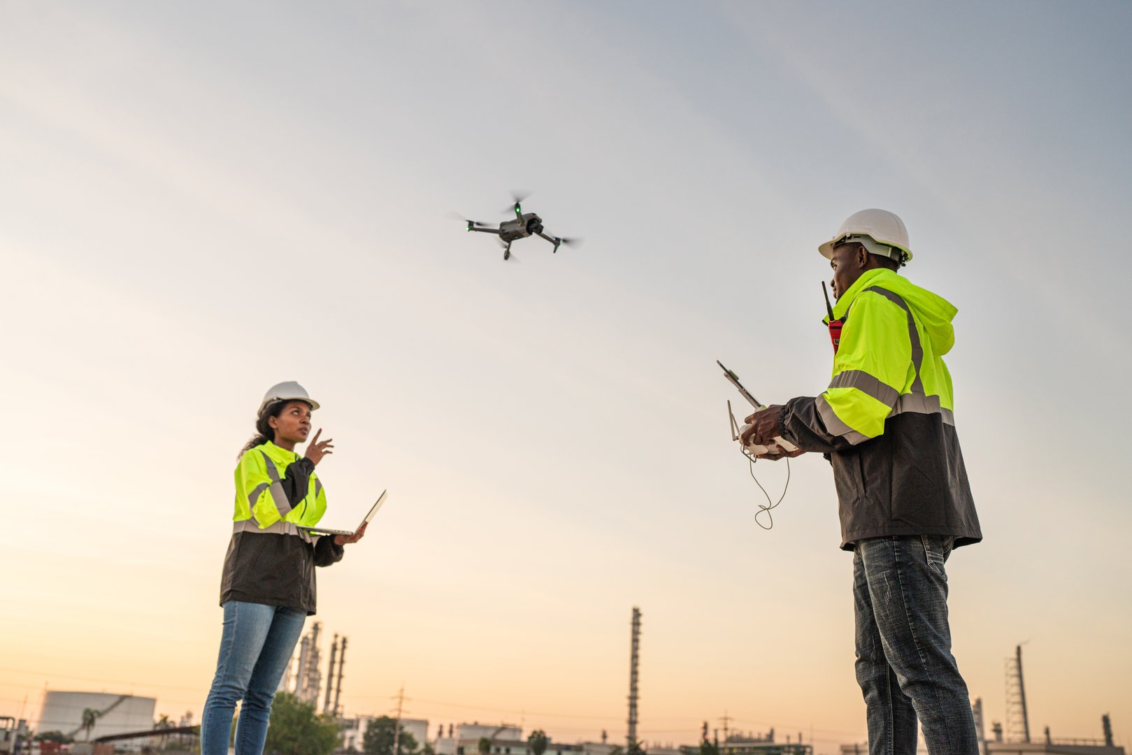 Team of Engineer Specialists Pilot Drone on Construction Site. Architectural Engineer and Safety Engineering Inspector Fly Drone at industrial plant.