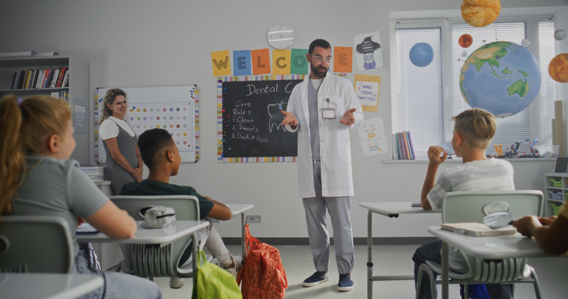 Dentist Visiting Classroom, Giving Lecture to Curious Primary School Students About Dental Care and Hygiene, Answering Questions. Young Kids Listening Attentively to Healthcare Worker. Slow Motion.