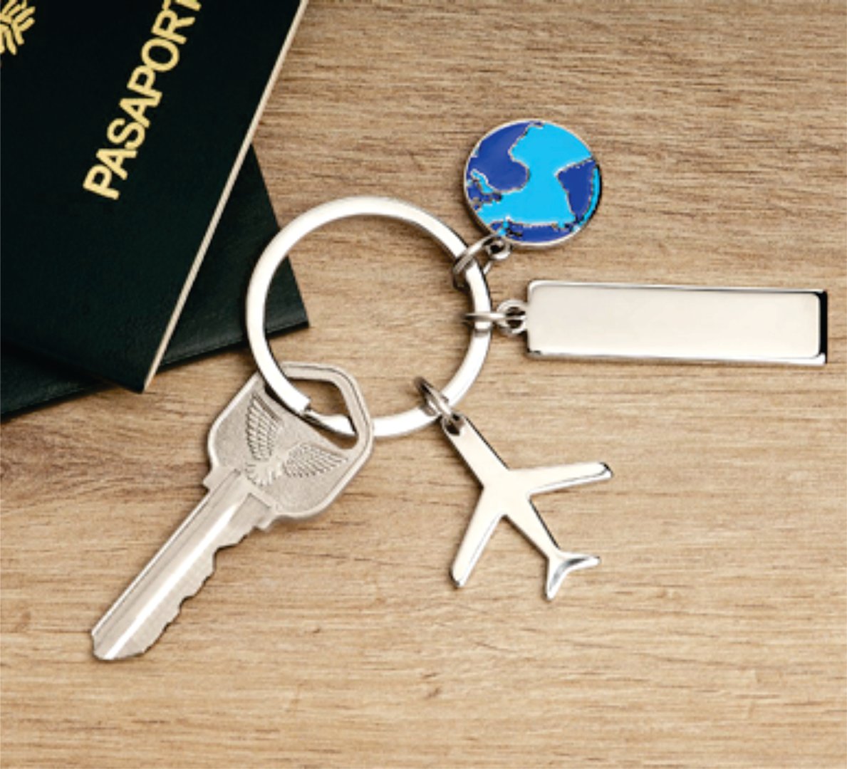 Keychain with airplane and world charms next to a passport on a wooden surface.
