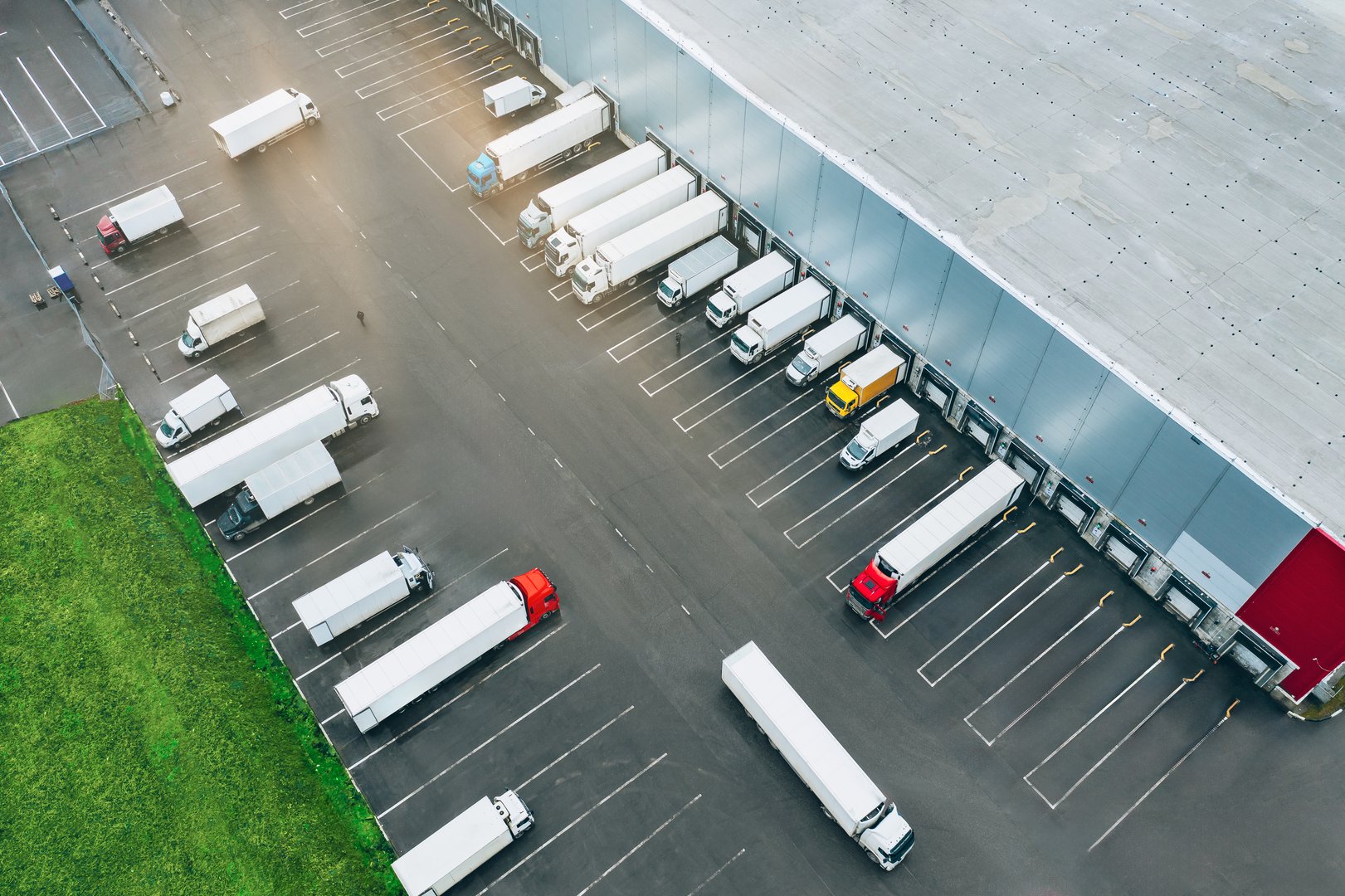 Aerial view of many trucks at the loading docks of a large distribution warehouse.