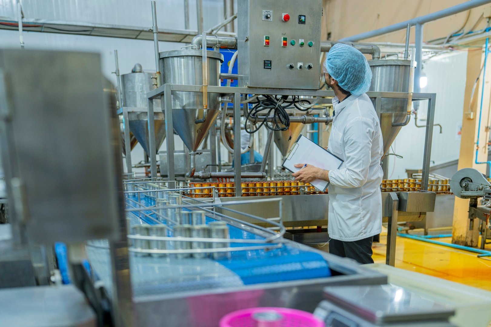A factory worker inspects advanced machinery in a modern food production facility, ensuring seamless operations and compliance with hygiene and safety standards for efficient manufacturing processes.