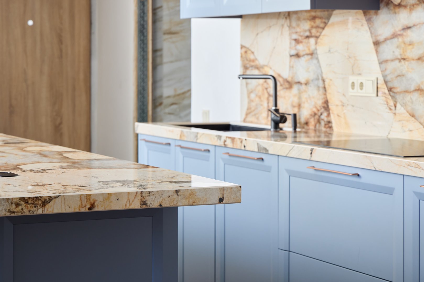 A beautifully stylish kitchen featuring eyecatching, vibrant blue cabinetry along with stunning marble countertops